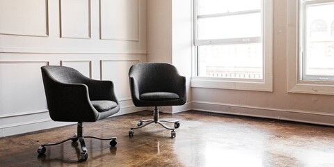 Modern office chairs in a minimalist office. The office chairs are black and placed on a polished floor. The minimalist office has large windows and clean lines. Aesthetic office interior and decor.
