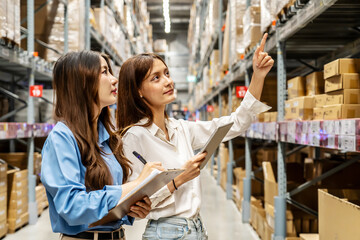 Two young asian women share insights and strategies while inspecting numerous packages and boxes engage in lively discussion while navigating a bustling warehouse filled with packages