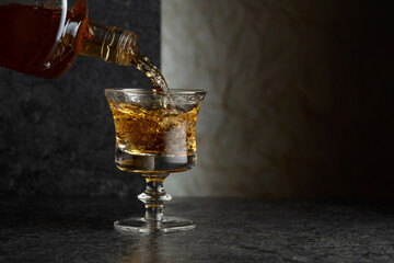 Pouring strong alcoholic drink from a bottle into a glass.