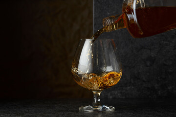 Pouring brandy from a bottle into a glass.