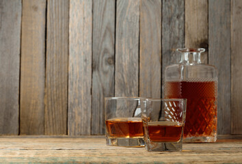 Glasses and decanter of whiskey on a old wooden table.