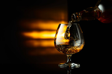 Pouring brandy from a bottle into a snifter.