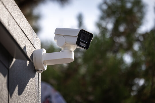 Surveillance camera CCTV. Close-up of modern surveillance cameras mounted on a dark building corner, ensuring security and monitoring, with a blurred tree background on a sunny day. Home security.