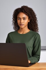 woman with curly hair sitting at a table with a laptop