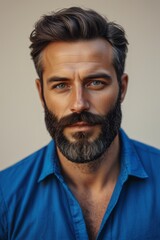 arafed man with a beard and a blue shirt looking at the camera