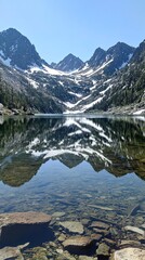 Crystal-clear lake reflecting towering snow-covered mountains.