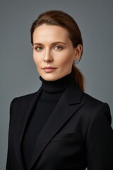 woman in black turtle neck sweater and black blazer posing for a picture