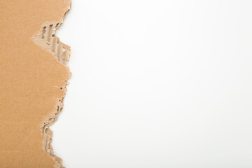 Torn light brown carton on light gray table background. Closeup. Empty place for text. Top down...