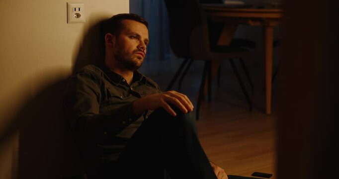 a young man sitting on the kitchen floor and sad, desperate