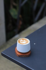 Coffee Cup Sits on Table with Latte Art and Rustic Wooden Coaster Perfectly