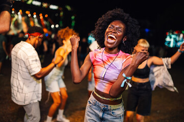 Enthusiastic young woman enjoying live music and dancing at night festival