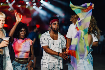 Young people dancing and enjoying music festival at night