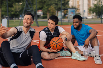 Fototapeta premium Three basketball players taking selfie after training session