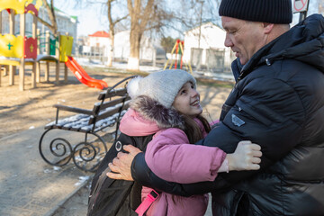 Grandfather walks with his granddaughter after school in the park in winter