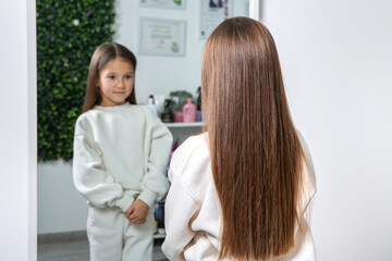 Fototapeta premium Adorable Little Girl Enjoying Her First Haircut in a Beauty Salon.