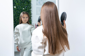 Fototapeta premium Adorable Little Girl Enjoying Her First Haircut in a Beauty Salon.