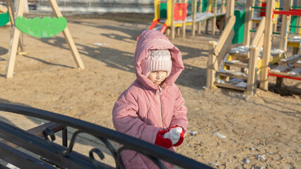 little girl playing on the playground on a winter day