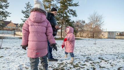 Grandfather walks with his granddaughters after school in the park in sunny winter day