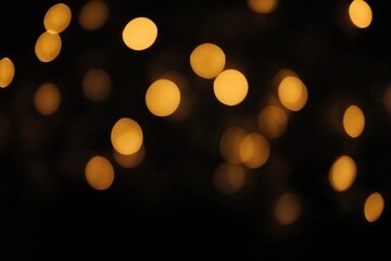 Fototapeta premium Golden bokeh lights creating a festive atmosphere on a black background