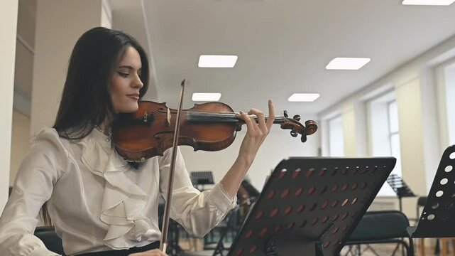 During an orchestral rehearsal, the violinist practices intricate passages. Precision and discipline shape the music, highlighting the dedication behind a grand performance