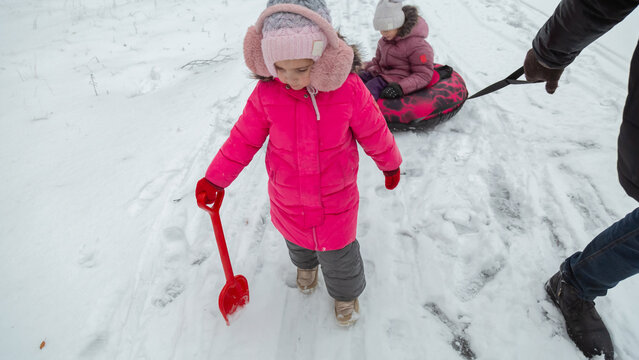 Father and daughters ride downhill on a Snow tubing in the park on the winter holidays