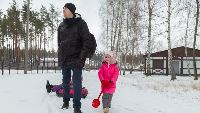 Father and daughters ride downhill on a Snow tubing in the park on the winter holidays