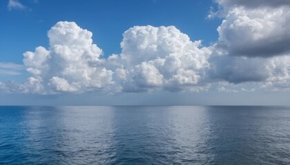 A calm ocean with blue water and white clouds in the sky