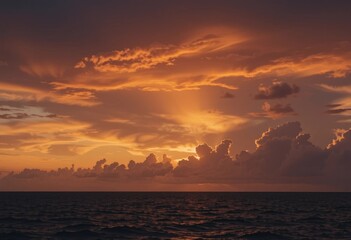 Naklejka premium A sunset over the ocean with vibrant orange and pink clouds in the sky