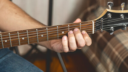 Guitar music. The performer plays. Practice chords. Male performer hands with fingers studying melody of song on electric string guitar fretboard indoors.