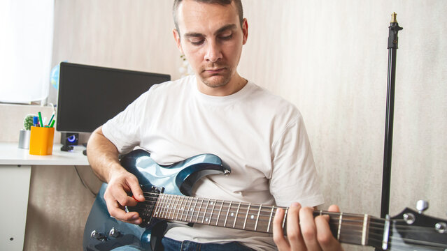 Guitarist. Focused man in headset enjoy creative hobby play electric guitar at home. Man musician practice in playing musical instrument