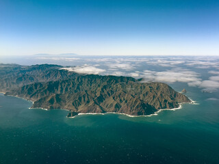 Spectacular aerial view of a volcanic island with rugged mountains and cliffs surrounded by the...