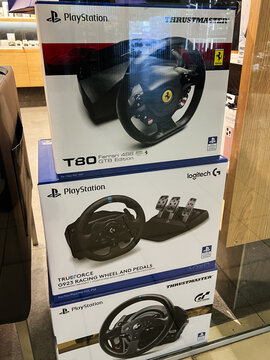 Kyiv, Ukraine - February 04, 2025: Stacked display of Play Station gaming racing wheels and pedals in retail store