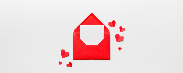 Red paper envelope with empty white card and heart on colored background. top view valentines day concept