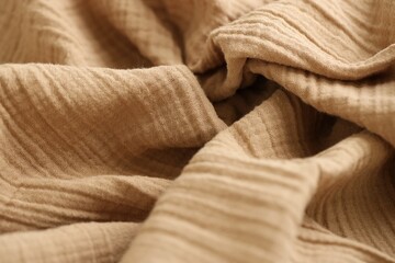 Texture of crumpled linen fabric under natural light in peach fuzz color