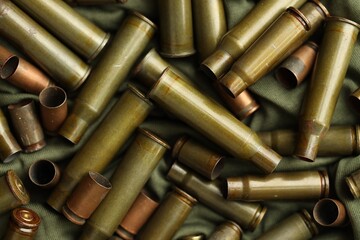 Many used rifle cartridges on military camo green fabric background