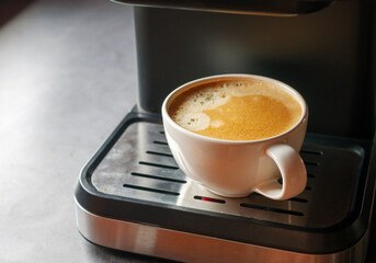 Close-up of espresso pouring from the coffee machine into a coffee cup. Coffee crema