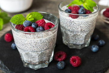 Healthy breakfast or morning with chia seeds vanilla pudding raspberry and blueberry berries on table background, vegetarian food, diet and health concept. Chia pudding with raspberry and blueberry
