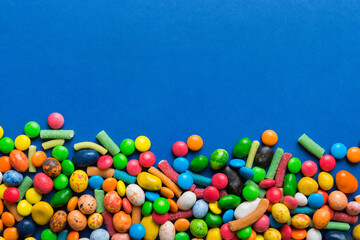 Mixed collection of colorful candy, on colored background. Flat lay, top view. frame of colorful chocolate coated candy