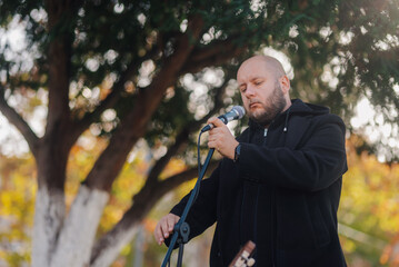 Singer performing live outdoors adjusting microphone