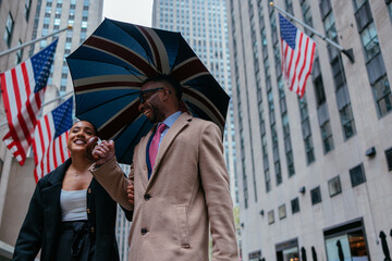 Business couple walking down new york city street sharing umbrella