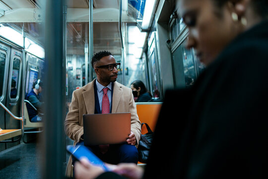 Businessman working on laptop on subway commuting home