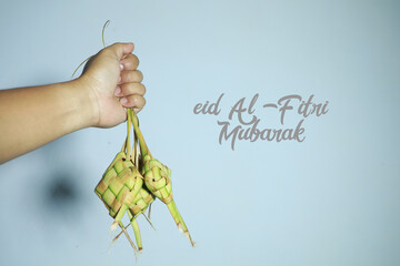 hands clutching a ketupat as a greeting for Eid al-Fitr