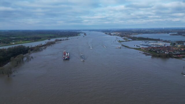 Aerial view of cargo vessels sailing on extremely wide Rhine river, after massive rainfall in Europe, near Tolkamer in the Netherlands
