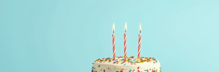 Celebratory birthday cake with candles and colorful sprinkles on light blue background