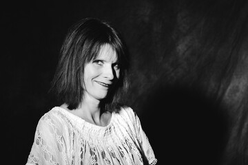 Ausdrucksstarkes Schwarz-Weiß-Porträt einer Frau mit langen Haaren und einem breiten Grinsen