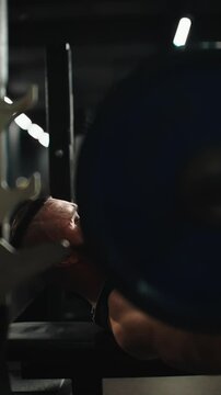 Muscular athlete lifting heavy barbell during intense bench press, displaying raw power and commitment in professional fitness environment