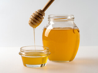 Natural organic honey in glass jar, honey dipper and honeycombs are near. Natural food background.