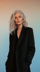 Elegant mature caucasian female in black coat with long silver hair against gradient background