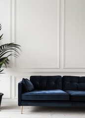 A navy blue velvet sofa with gold legs in a modern living room with white walls and a potted plant