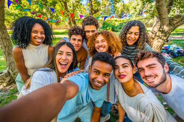 Multi-ethnic happy friends taking selfie celebrating party at park